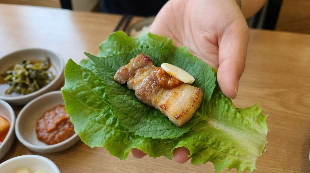How to eat Korean BBQ ssam with lettuce, perilla leaf, grilled pork belly, and ssamjang